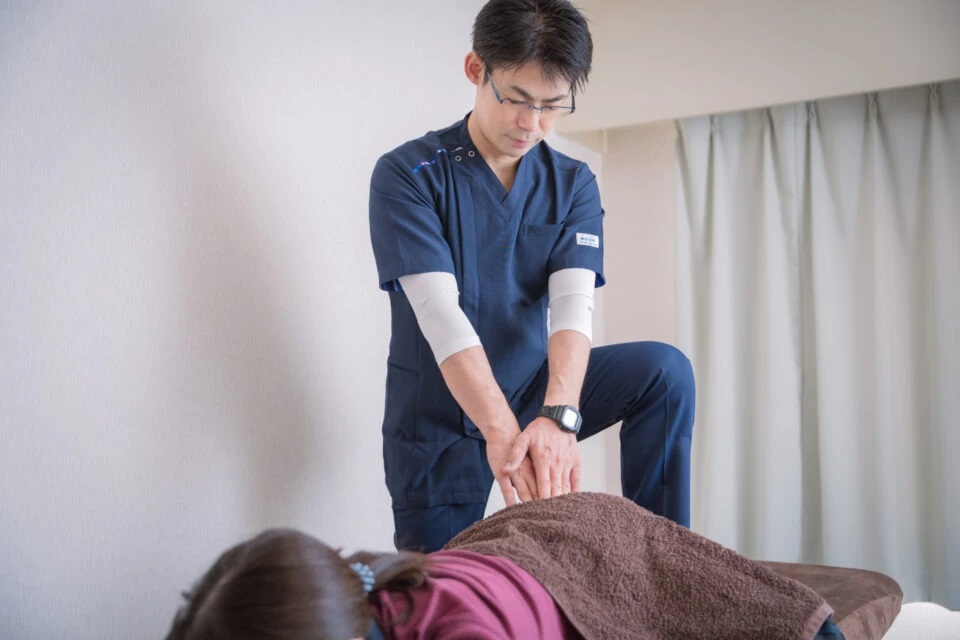 肩をほぐす男性スタッフ